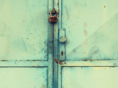 Eskimiş kilitleme sistemi olan eski endüstriyel metal kapı. Eski yeşil levha, metal kapı, soyulmuş boya ve pas..