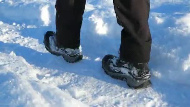 他走在厚厚的雪地里时 一双黑色的隔热冬靴和覆盖着雪的户外隔热裤 — 图库视频影像