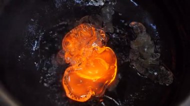 Erimiş cam damlaları atık madde ve buhar artışları arasında kabın içine damlıyor. Bir cam fabrikasında cam kırıkları var..