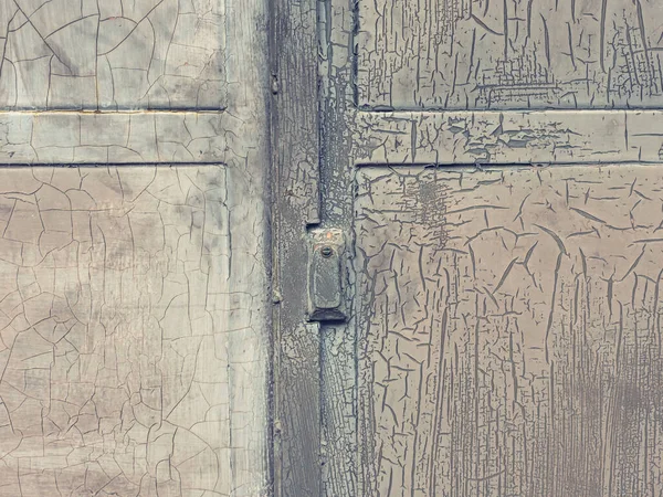 Closed industrial door locked with safetuy lock. Weathered pant on door metal surface