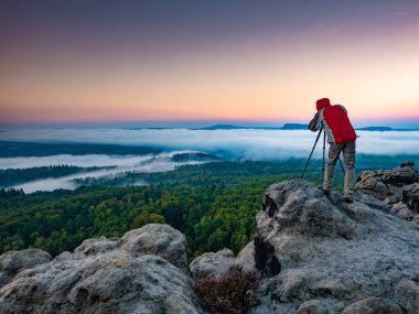Dijital kameralı gezgin manzara fotoğrafçısı sabah sisli ülkesinin fotoğrafını çekiyor.