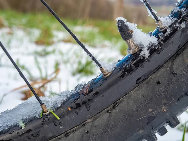 Presta valve stem of inner tube of MTB wheel. Snowy and icy rim of mountain bike after ride in sn owy landscape.