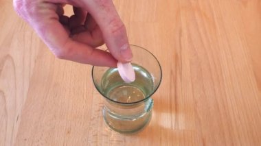 Su ve coşkulu tabletten su doldurup köpük hazırlamak. Mutfaktaki tahta masa..