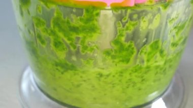 Mutfakta sağlıklı meyve püresi hazırlayan kadın. Blender yeşil sebze ve otları kesip karıştırıyor..