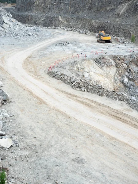露天掘りで土の移動に取り組んでいる掘削機 バックホーは採石場で花崗岩砂利を掘る — ストック写真