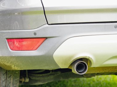 Araba egzoz borusu, arka alçak açılı görüş. Kısa çimlere park eden araba.