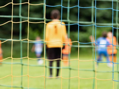 Futbol kapısı ağından bak. Kaleci, rakiplerin saldırısı sırasında yavaşça geri çekiliyor. Soyut görünüm