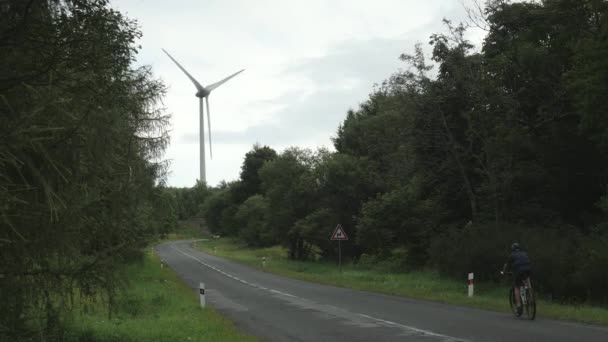 Windkraftanlage Über Der Landschaft Radfahrer Und Autos Auf Der Asphaltierten — Stockvideo