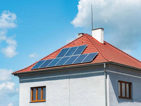 家族の家のタイル張りの屋根の上の電気ソーラーパネル 家の断熱ファサードは そのエネルギー強度を低下させます — ストック写真