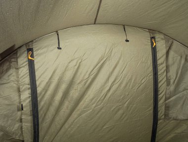 Çadırın hamile kalmış kumaşında su damlacıkları. Açık yeşil fiber kumaş üzerinde yağmur suyu damlaları