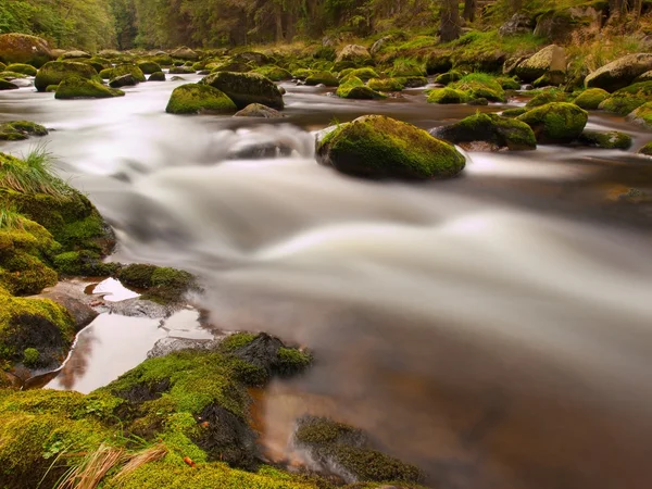 Big red and mossy boulders in foamy water of mountain river in forest. Light blurred water with reflections. — Stock Photo, Image