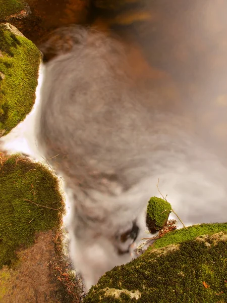 Mossy stone in blurred colorful waves of mountain stream. Cold water is running and turning between boulders and bubbles create trails on level. Colorful bubles on stones and into water. — Stock Photo, Image