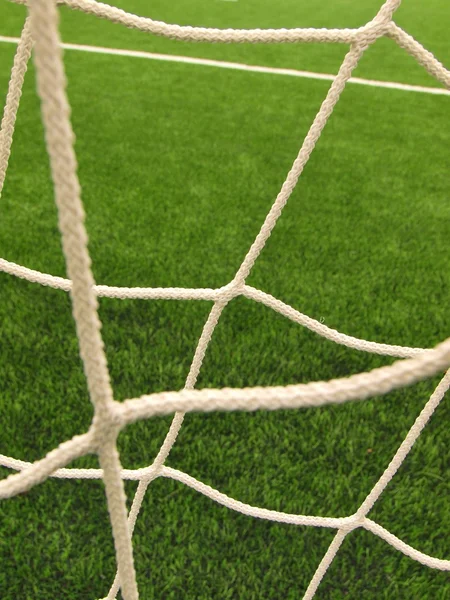 Držte ohnutý fotbalové sítě, fotbal fotbal čisté. plastové trávy a bíle natřené linie na fotbalové hřiště v pozadí — Stock fotografie