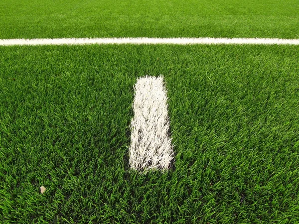 Closeup view to white lines on artificial grass field on football playground. Detail of a cross of lines in a soccer field. Plastic grass and finely ground black rubber — Stock Photo, Image