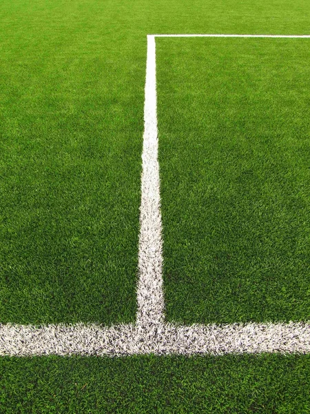 Vista de cerca de las líneas blancas en el campo de césped artificial en el patio de fútbol. Detalle de una cruz de líneas en un campo de fútbol. Hierba plástica y caucho negro finamente molido — Foto de Stock