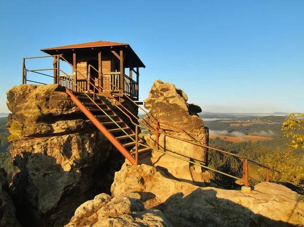 Herbstliche Szene am frühen Morgen. Holzhütte auf Hauptfelsen als Aussichtspunkt, dunkler Himmel, weißer Herbstnebel im Tal. — Stockfoto