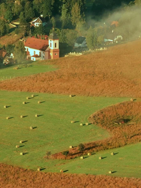 Lever de soleil ensoleillé dans une belle campagne du parc Suisse Tchèque-Saxe. Doux brouillard au-dessus de l'église du village. Les rayons chauds du soleil combattent avec la brume froide du sol dans la vallée . — Photo