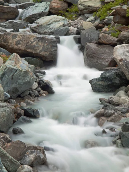 Ripido letto di torrente pietroso del ruscello alpino. Onde sfocate di torrente che scorrono su massi e pietre, alto livello dell'acqua dopo forti piogge . — Foto Stock