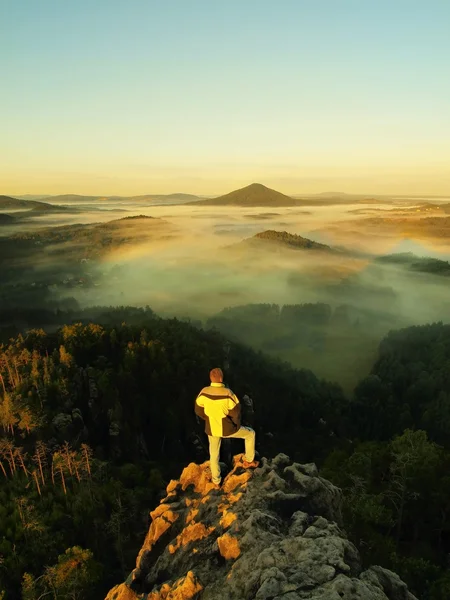 Adam kalış kayalık tepe üzerinde ve içinde sabah puslu ve sisli vadinin daybreak göz kulak. güzel bir sonbahar sabahı. — Stok fotoğraf