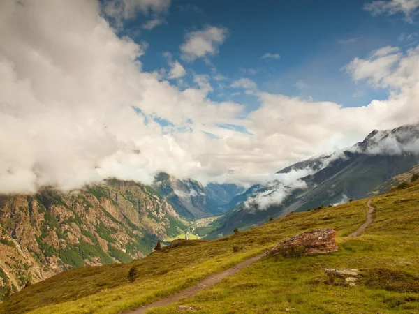 Scherpe besneeuwde toppen van de Alpen bergen boven de vallei vol met zware mist — Stockfoto