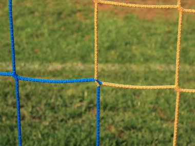 Çapraz mavi sarı dize futbol ağlarının detayını. Çim futbol bahçesi içinde belgili tanımlık geçmiş.