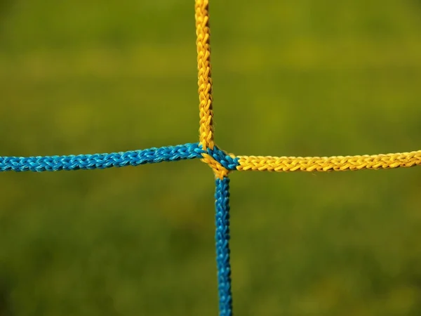 Detail of crossed soccer nets, soccer football in goal net with grass on football playground in the background — Stock Photo, Image