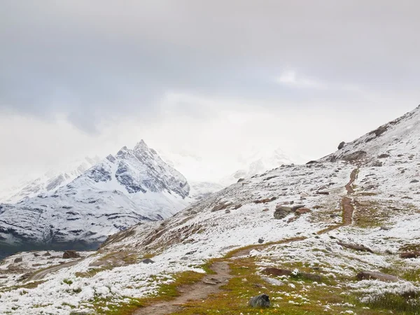 Snöiga landskap med kilometerlång väg. dimmiga skarpa toppar av höga berg i bakgrunden. — Stockfoto