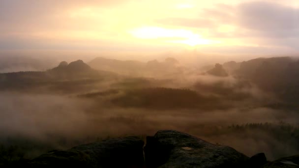 Amazing sunrise in a beautiful mountain of Czech-Saxony Switzerland park. Rocky hills peaks increased from foggy background, the fog is orange due to sun rays. — Stock Video