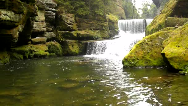 Cascade de déversoir sur le ruisseau de montagne, l'eau coule sur les blocs de grès et les bulles créent sur le niveau de l'eau laiteuse . — Video