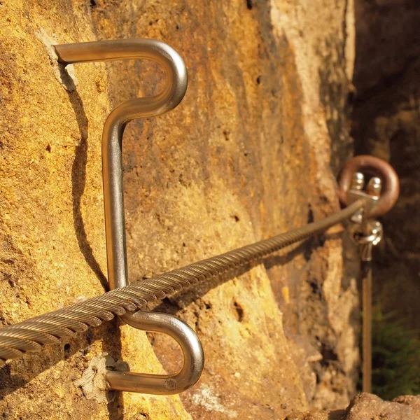 Climbers way. Iron twisted rope fixed in block by screws snap hooks