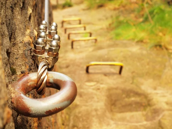 Iron twisted rope fixed in block by screws snap hooks. Detail of rope end anchored into sandstone rock — Stock Photo, Image