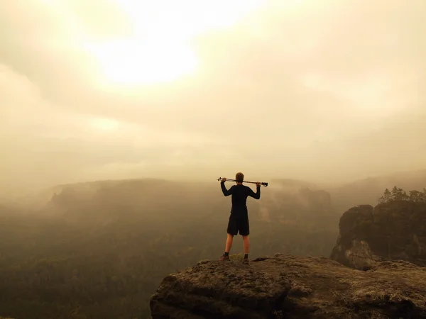 Turista con postes está de pie en el punto de vista rocoso y mirando en el paisaje nublado de la mañana. Parque nacional del imperio del rock, melancólica mañana de otoño . — Foto de Stock