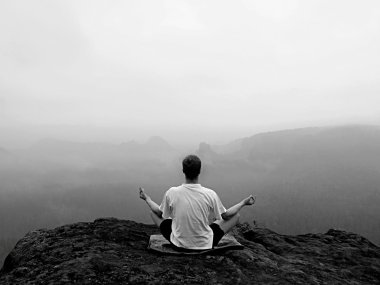 Adam kayalar tepe üzerinde Yoga poz puslu sabah içinde yapıyor