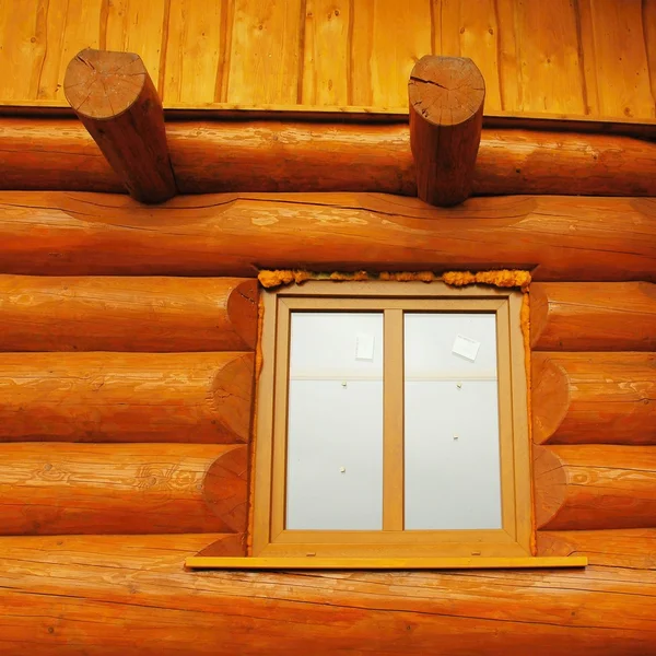 Detail of window built in wooden beams cabin wall. Painted wood with fungicide light red paint.