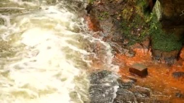 Hızlı tam akan köpüklü su kumtaşı kaya, turuncu çökeller kirli banka arasında. Kumtaşı bloğu içine hewed derin nehir yatağı
