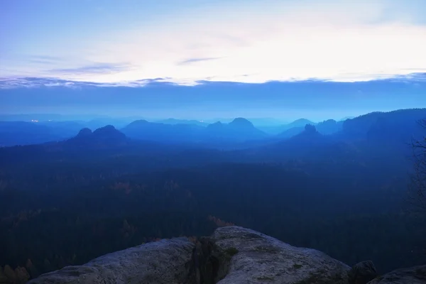 Kalter nebelblauer Morgen. eine Minute vor Sonnenaufgang in einem wunderschönen Tal mit felsigem Park. Sandsteingipfel aus blauem Nebel. — Stockfoto