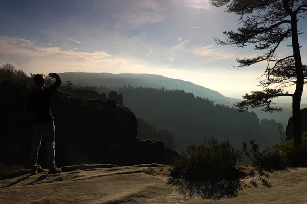 O homem senta-se no pico no parque dos impérios da rocha e observa sobre o vale misty do outono. Dia de outono ensolarado . — Fotografia de Stock