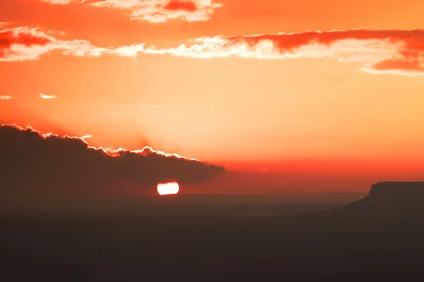 Autumn rocky landscape within sunset. Colorful sky above deep misty valley full of evening humidity. Sun on horizon. — Stock Photo, Image