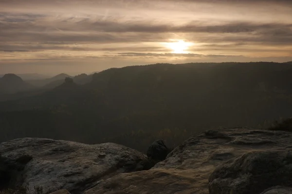 Zonsondergang in een prachtige rotsachtige park Boheemse-Saksen Zwitserland. Zandsteen pieken en heuvels steeg van mistige achtergrond, de mist is oranje als gevolg van zonnestralen. — Stockfoto