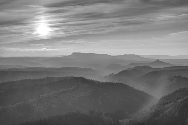 Sunset in a beautiful rocky park Bohemian-Saxony Switzerland. Sandstone peaks and hills increased from foggy background, the fog is orange due to sun rays. — Stock Photo, Image