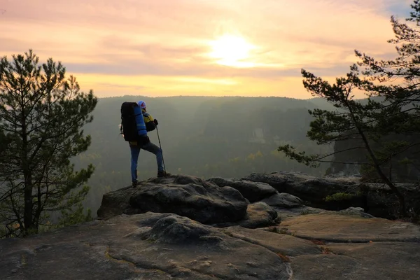 Turista com grande mochila em pé no ponto de vista rochoso e observando a paisagem nebulosa da manhã. Parque nacional Saxon Suíça na Alemanha. manhã de outono melancólica . — Fotografia de Stock