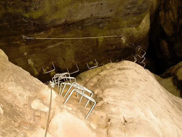 Железные судороги в скале, туристическая лестница. Железная скрученная веревка, закрепленная в блоке винтами крючками. Верёвка закреплена на скале из песчаника. Альпинисты . — стоковое фото