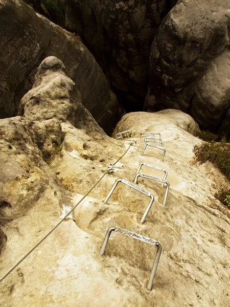 Železný křeče v rock, turistické žebřík. Železo kroucené lano v bloku odstraněných šroubů Karabinky. Konec provazu, který je ukotven do pískovcové skály. — Stock fotografie