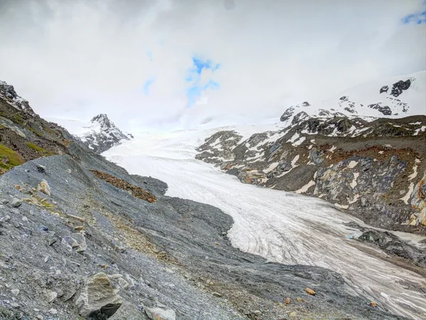 Iceberg Findelgletscher in stony valley bellow Adlerhorn massif, Zermatt region, Switzerland. The rest of ice at end of autumn, first snow on rocky peaks above — Stock Photo, Image