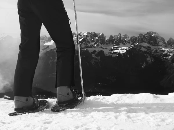 Tourist in black with snowshoes standing on snowy view point. National park Alps park in Italy. Sunny winter mountains. — Stock Photo, Image