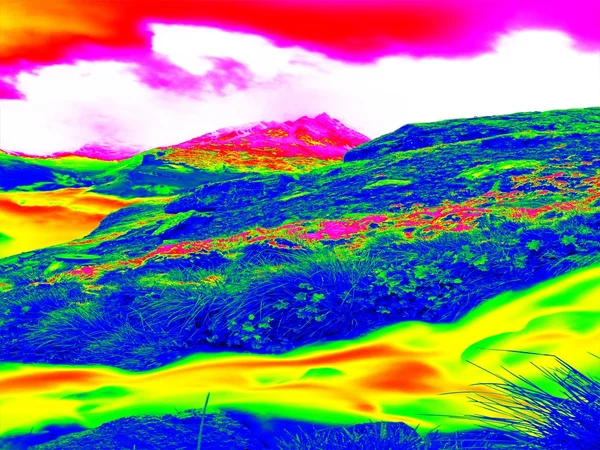 Alpine spring mountain path in infrared photo. Hilly landscape in background. Sunny weather with clear sky above. Amazing thermography colors.