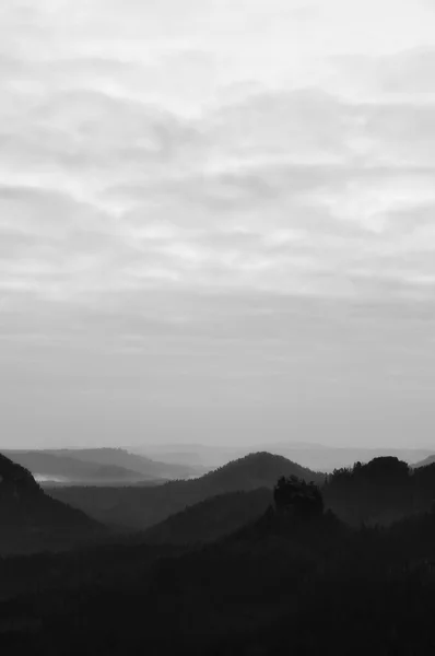 Outono nascer do sol panorama em uma bela montanha dentro de inversão. Picos de colinas aumentou a partir de fundo nevoeiro. Foto em preto e branco — Fotografia de Stock