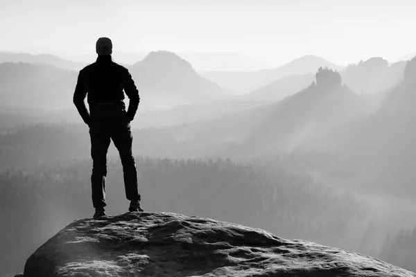 Hiker is standing on the peak of sandstone rock in rock empires park and watching over the misty and foggy morning valley to Sun. Beautiful moment the miracle of nature — Stock Photo, Image