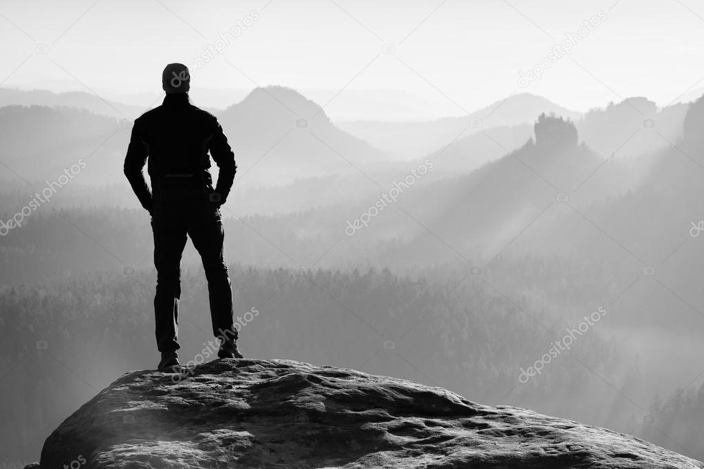 Hiker is standing on the peak of sandstone rock in rock empires park and watching over the misty and foggy morning valley to Sun. Beautiful moment the miracle of nature