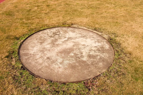 Concrete manhole cover drainage system in the midst of cropped dry grass — Stock Photo, Image